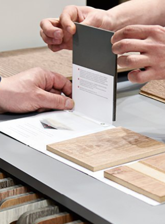 Kundenberatung im Fachhandel: Zwei Personen begutachten verschiedene Materialmuster für Bodenbeläge.