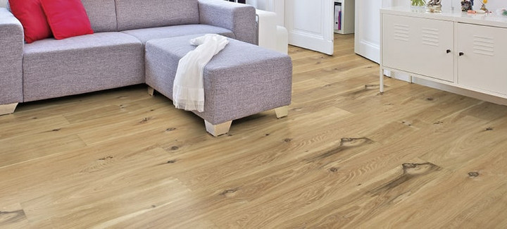 Im Wohnzimmer ist Parkett in Langdielen-Optik verlegt. Dazu passt ein Ecksofa mit bunten Kissen.