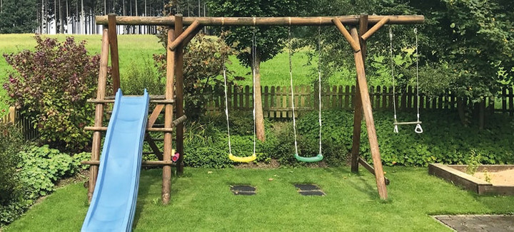 Spielgeräte: Schaukel und Rutsche für Kinder im Garten.