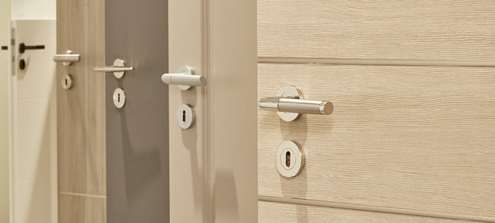 Mehrere nebeneinander angeordnete Türblätter in unterschiedlichen Farbtönen (weiß, holzähnlich, grau) mit integrierten Türgriffen.