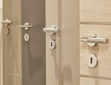 Mehrere nebeneinander angeordnete Türblätter in unterschiedlichen Farbtönen (weiß, holzähnlich, grau) mit integrierten Türgriffen.